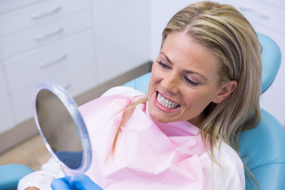 Emergency Cosmetic Dentistry | Patient looking at mirror.