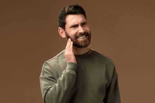 man in pain touching cheeks