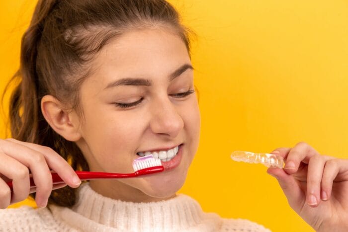 woman holding tooth brush and invisalign