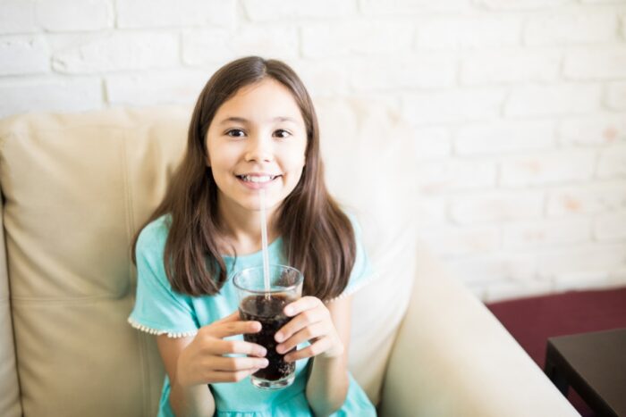 Child drinking a sugary soft drink highlighting healthy oral habits for kids
