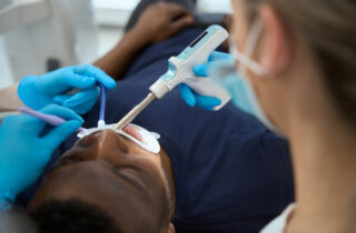 Dentist treating patient with a dental tool during an oral health procedure now.