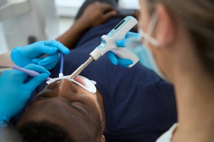 Dentist treating patient with a dental tool during an oral health procedure now.