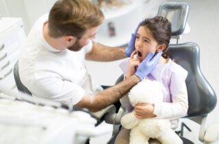 Young girl at first dental visit holding teddy bear