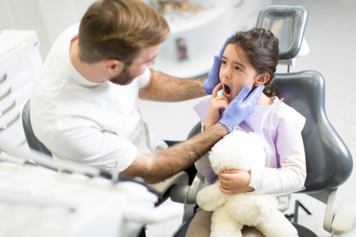Young girl at first dental visit holding teddy bear