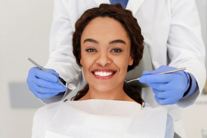 Smiling woman at dentist showing need for timely dental visits